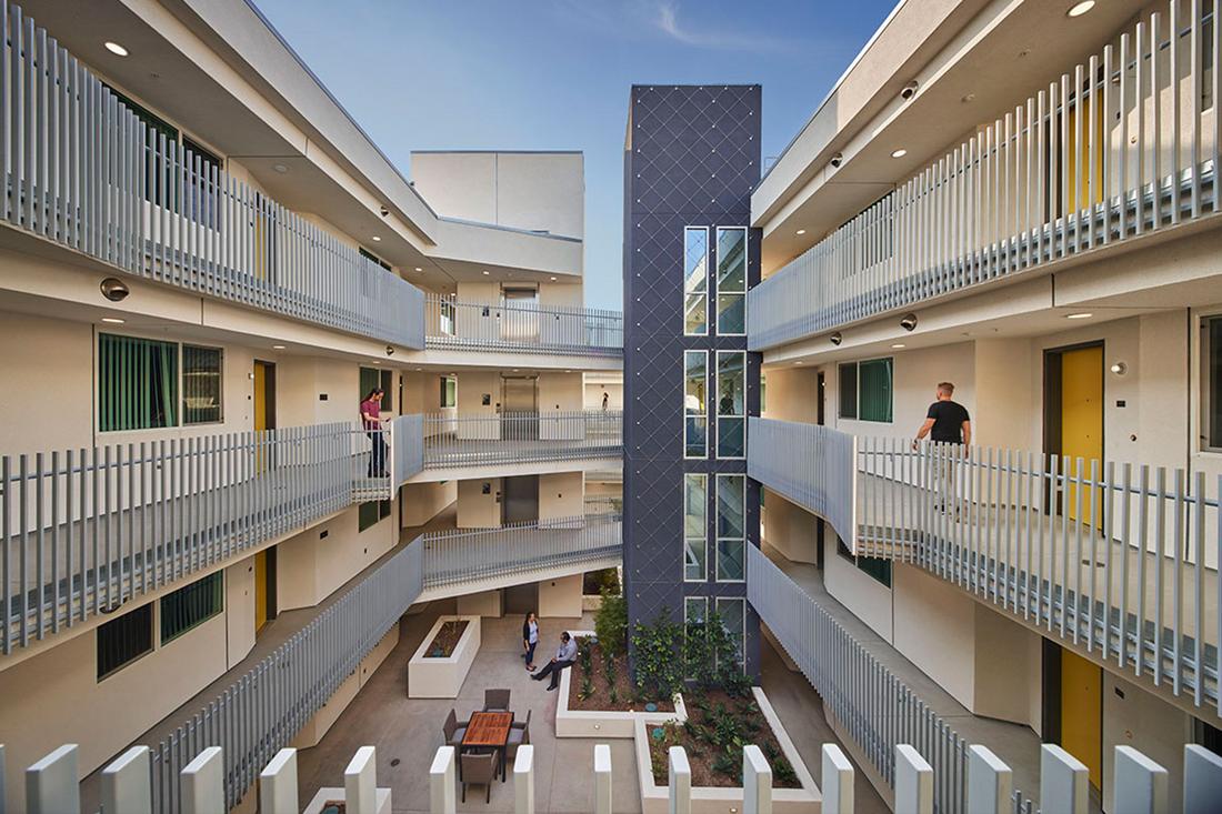 a group of people standing in a building with balconies.