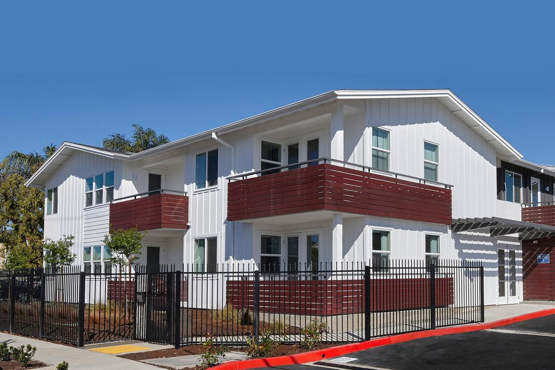 a white and red apartment building with a black fence.